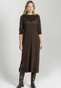 Brązowa dzianinowa sukienka z szerokim dekoltem, rękawami do połowy przedramienia oraz subtelnymi poziomymi paskami. Posiada boczne rozcięcia i teksturowane wykończenie na dole.