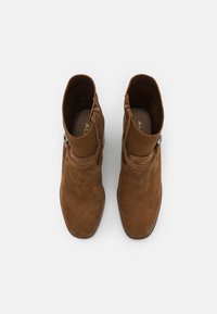 Cizme ankle din suede maro, cu guler din material negru texturat, fermoar lateral și vârf rotund. Toc plat și design minimalist.