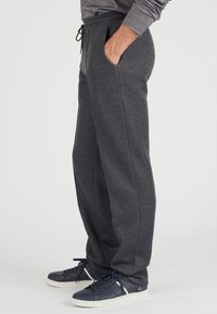 Grijze sweatpants met een verstelbare taille, zijzakken en een taps toelopend ontwerp. G gedragen met donkere sneakers voor contrast.