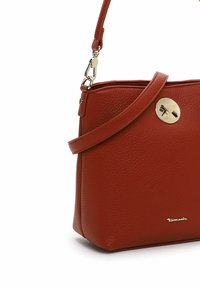 Bolso de cuero texturizado rojo con un cierre de hardware en tono dorado suave, correa ajustable y detalle de logo en relieve en la parte inferior.