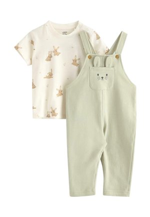 Kremowa koszulka dla niemowląt z krótkim rękawem i beżowym nadrukiem królika, zestawiona z jasnzielonymi ogrodniczkami z nadrukiem twarzy królika i uszami na przedniej kieszeni.