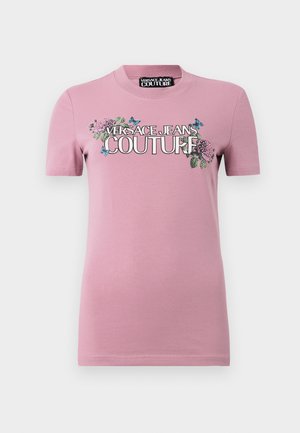 Rosa bomull T-skjorte med korte ermer og rund hals. Frontgrafikken inkluderer blomsterprikker og "VERSACE JEANS COUTURE" i fete bokstaver.