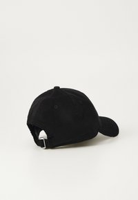 Black corduroy cap featuring a curved brim, adjustable metal buckle, and stitched eyelets for ventilation. Textured fabric surface.