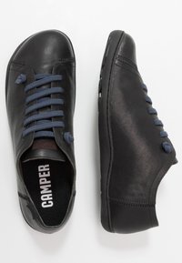Zapatos de cuero negro con punta redonda y cordones azul marino. Presentan una superficie texturizada y detalles bordados en la parte superior y los lados.