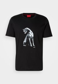 Black cotton t-shirt featuring a graphic of a seated dog in white and gray tones. Round neckline and red interior tag with “HUGO” branding.
