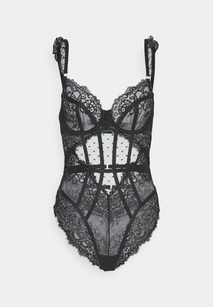 Body en dentelle noire avec bonnets structurés, bretelles réglables et motifs floraux détaillés. Panneaux transparents avec bords festonnés et un crochet central.