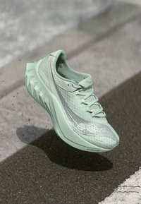 Light green running shoe with a textured upper, a lace closure, and a geometric sole pattern. Features a silver accent along the side.