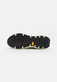 Sola de borracha preta com padrão de aderência agressivo, apresentando uma borda bege e um proeminente logo da Vibram amarelo no centro.