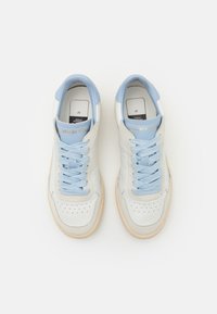 Baskets en cuir blanc et bleu clair avec lacets, nom de la marque sur la languette, et semelles en caoutchouc beige, vues de dessus sur un fond blanc.