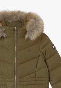 Pufferjack in olijfgroen met een afneembare bontkap. Voorzien van een ritsluiting en chevronstiksel. Logo detail op de mouw.