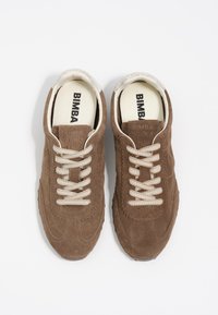 Brązowe zamszowe sneakersy z kremowymi sznurówkami i teksturowaną podeszwą. Posiadają obszycia oraz logo na wkładce.