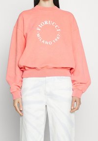 Koraalkleurige sweatshirt met witte tekst "Fiorucci Milano 1967" in een rond ontwerp, met ribgebreide boorden en zoom, en een ontspannen pasvorm.