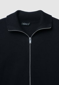 Schwarzer Reißverschluss-Pullover mit gerippter Textur, hohem Kragen und silbernem Reißverschlussdetail. Das Etikett trägt "CALLIOPE", Größe L.