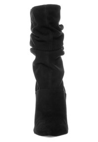 Stivale alla caviglia nero in suede, con punta affusolata, tacco spesso e cuciture visibili lungo i lati. Texture liscia.
