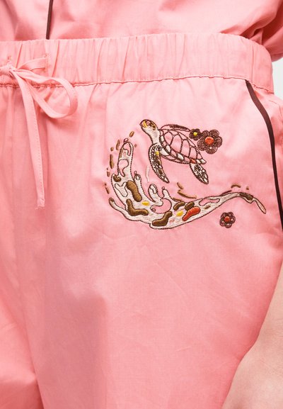 Różowa tkanina z elastycznym pasem i kokardką, ozdobiona haftowanym żółwiem morskim z kwiatowymi akcentami oraz abstrakcyjnym wzorem fal.