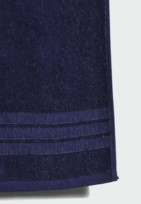 Ciemnoniebieski ręcznik o teksturowanej powierzchni, z poziomymi, paskowymi akcentami na dole oraz miękkim, puszystym wykończeniem.