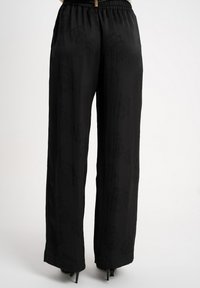 Czarne spodnie o szerokich nogawkach wykonane z miękkiego, gładkiego materiału, z subtelnym kwiatowym wzorem i elastycznym pasem z ozdobnym akcentem.