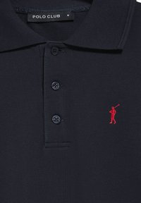 Marinblå polotröja med en texturerad mönster, utrustad med tre svarta knappar och en liten röd broderad golfspelare ikon på vänster bröst.