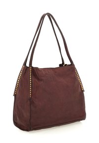 Borsa a tracolla in pelle marrone con due lunghe cinghie, borchie dorate lungo le cuciture laterali e una forma rettangolare leggermente inclinata.