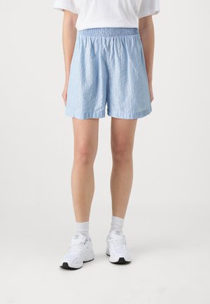 Light blue striped shorts with an elastic waistband, featuring a relaxed fit and soft texture, paired with white athletic shoes and socks.