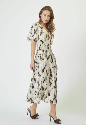 Knee-length dress with a white base featuring black and brown abstract patterns, puff sleeves, and a V-neckline; paired with open-toe heels.