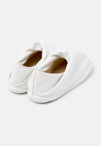 Scarpe slip-on in pelle bianca con un design morbido e arricciato e una superficie liscia, caratterizzate da una punta arrotondata e una costruzione minimalista e senza cuciture.