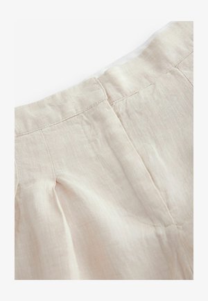 Pantaloni in lino beige con un design plissettato, orlo sfrangiato e vita cucita. La texture del tessuto appare morbida e leggera.