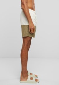 Shorts de bain en blanc et vert olive, dotés d'une taille élastique avec cordon de serrage, fabriqués en tissu léger et avec une coupe décontractée.