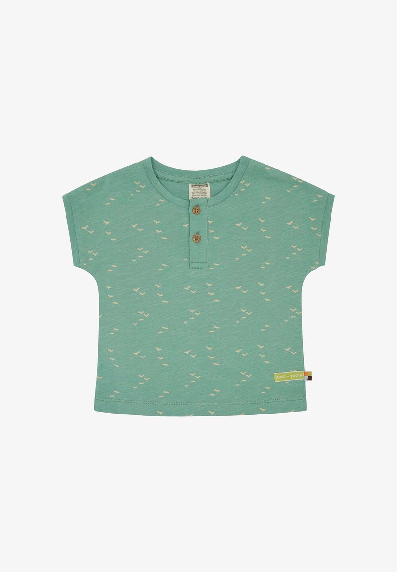 Short-sleeve green cotton shirt with small beige bird patterns, two wooden buttons at the neckline, and a colorful label at the side hem.