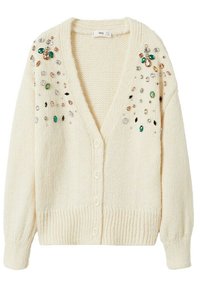 Cardigan crème en maille avec un col en V, orné de pierres décoratives vertes, dorées et transparentes le long des épaules et de la patte de boutonnage avant.