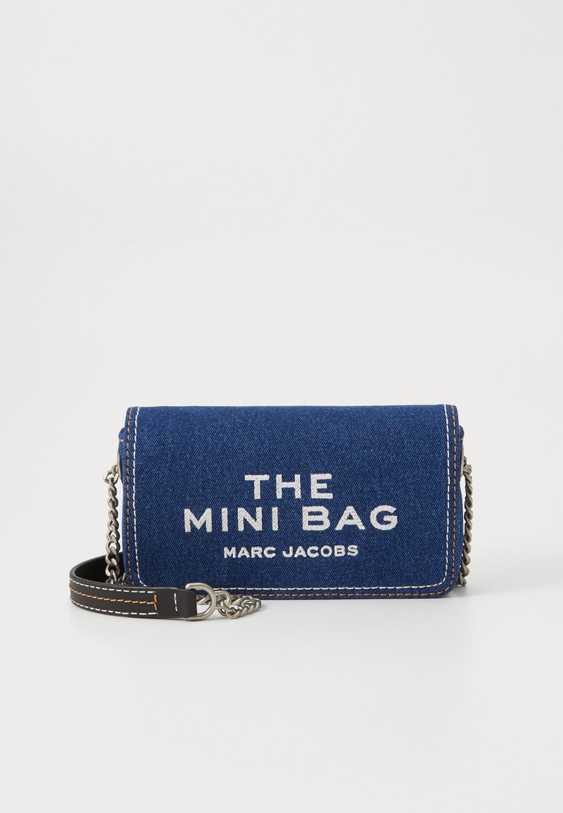 Geantă mini din denimul albastru, cu text alb în relief "THE MINI BAG" și "MARC JACOBS." Dispune de o curea din lanț argintie și accente de cusătur�ă în contrast.
