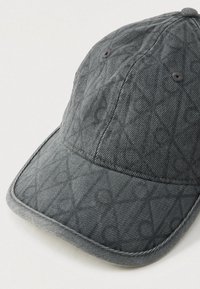 Quiltet mørkegrå baseballcap med synlige stikninger og ventilasjonsøyer, vist på en ensfarget lys overflate.