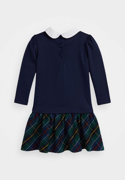 Robe longue à manches longues bleu marine avec un col blanc, trois boutons dans le dos et une jupe à carreaux dans des tonalités vertes, bleues, rouges et jaunes.