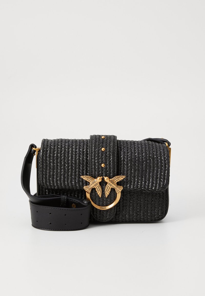 Svart vevd crossover-veske med bred lærrem, gullfuglformet lås og gullnagledekorasjoner på forsiden av klaffen.