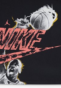 Schwarzes T-Shirt aus Stoff mit einem großen Grafikdesign, das "NIKE" in leuchtendem Pink zeigt, und einem Basketballspieler in Graustufen mit gelben Akzenten.