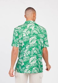 Groene shirt met korte mouwen, voorzien van een wit tropisch bladpatroon, met kraag en een losse pasvorm, gemaakt van lichtgewicht stof.