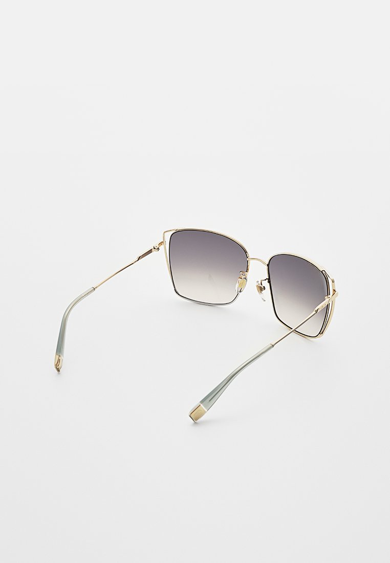 Gafas de sol con montura de metal dorado y lentes cuadrados que degradan de negro a gris. Patillas delgadas con un acabado en verde claro y extremos dorados.