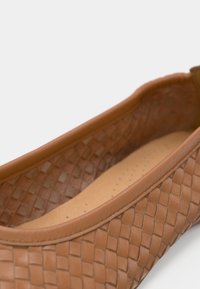 Καφέ επίπεδο παπούτσι από ύφαντο δέρμα με λεία, στρογγυλεμένη μύτη και ταμπά εσωτερικό με διάτρητες λεπτομέρειες για αναπνοή.