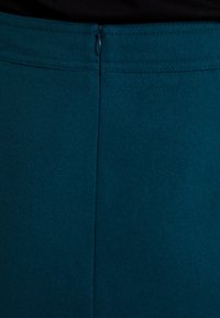 Gonna di lana verde acqua con una texture liscia, dotata di una zip nascosta sul retro e di cuciture pulite per un aspetto aderente.