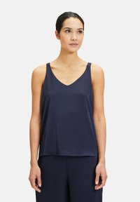Granatowa satynowa cami z dekoltem w literę V, cienkimi ramiączkami, luźnym krojem i gładką fakturą. Idealna do noszenia na warstwy lub w codziennych stylizacjach.