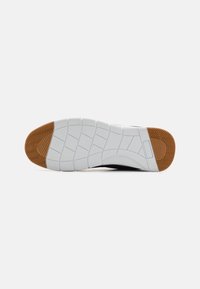 Shoe sole featuring a white rubber base with a textured pattern and a brown accent at the toe, designed for traction and durability.