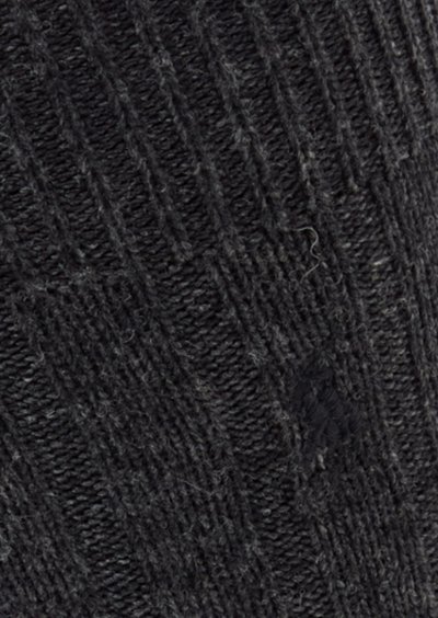Czarna dzianinowa skarpeta o prążkowanej fakturze, z ukośnym wzorem i subtelnymi różnicami odcieni. Wykonana z miękkiego, ciepłego materiału.