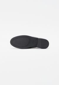 Black rubber shoe sole with textured surface and oval patterns. Features a slightly raised heel and a smooth central area.