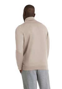 Maglione beige a maglia con collo alto, maniche lunghe, polsini e orlo a coste. Texture liscia e motivo sottile visibile dal retro.