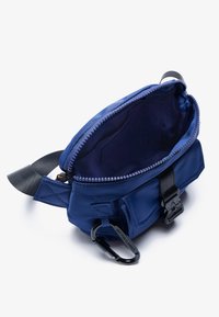 M�ørkeblå nylon taske med en lynlåslukning, indvendig foring og en clipskrog. Har en forlomma og sorte remdetaljer.