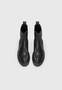 Bottines en cuir noir avec un design élégant, des panneaux latéraux élastiques et une semelle en caoutchouc texturée pour une meilleure adhérence. Bout arrondi et languettes de tirage.