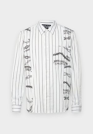 Balta garām piedurknēm krekls ar melnām vertikālām svītrām, ar grafiskiem attēliem un tekstu kreisajā pusē un krūšu kabatu.