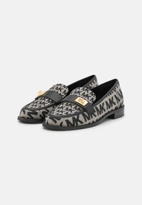 Mocassins tissés en noir et beige avec un motif géométrique, dotés d'une lanière en cuir noir et d'un accent logo doré à l'avant. Talon carré bas.