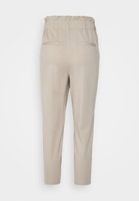 Beiga avsmalnande byxor med elastisk midja och två bakfickor, visade från baksidan mot en vit bakgrund.