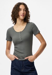 Top cinza de malha canelada com mangas curtas e decote redondo, com cinco botões; combinado com calças de ganga azul-escuro.